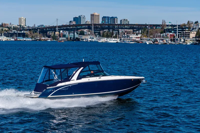 Slide: The Image of 2019 Cobalt R30 boat cruising on a vibrant blue lake with cityscape background. - 28