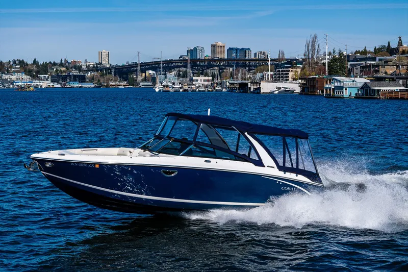 Slide: The Image of 2019 Cobalt R30 boat cruising on a vibrant blue lake with cityscape background. - 29