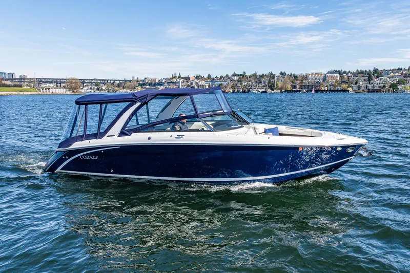 Slide: The Image of 2019 Cobalt R30 boat cruising on a scenic lake with city skyline in background. - 3