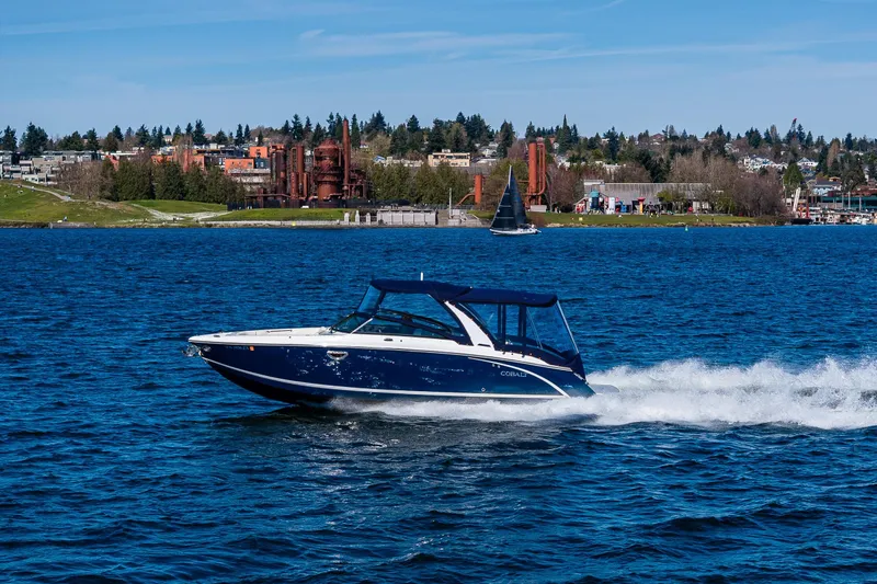 Slide: The Image of 2019 Cobalt R30 boat cruising on a scenic lake with industrial backdrop. - 30