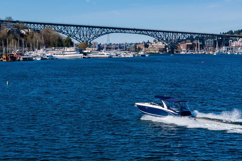Slide: The Image of 2019 Cobalt R30 boat cruising on a vibrant blue lake with a bridge in the background. - 31