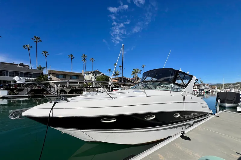 The Image of 2007 Larson Cabrio 310 boat docked in a marina under a clear blue sky. - 0