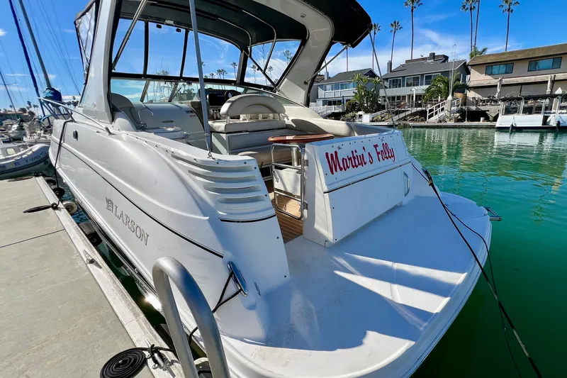 Slide: The Image of 2007 Larson Cabrio 310 boat docked in marina, sunny day, palm trees in background. - 11