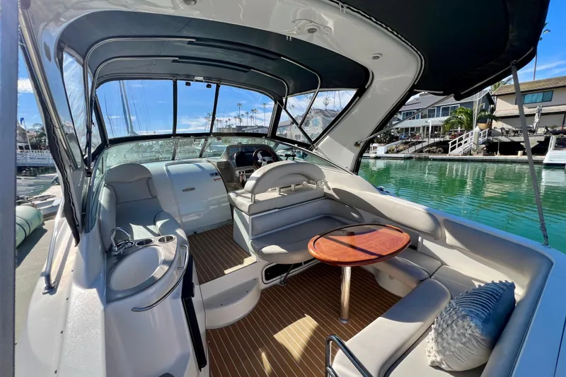 Slide: The Image of 2007 Larson Cabrio 310 boat interior with seating and table, docked by waterfront homes. - 12