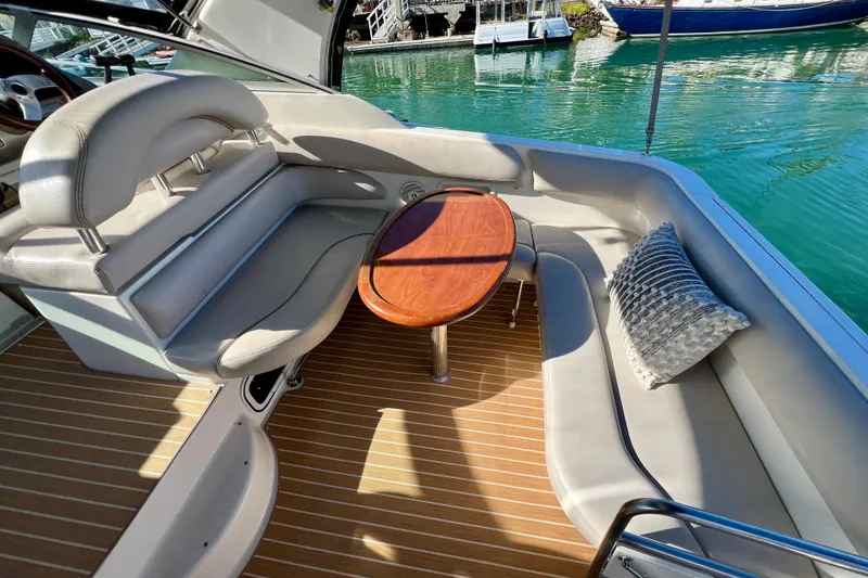 Slide: The Image of 2007 Larson Cabrio 310 boat interior with cushioned seating and wooden table. - 15