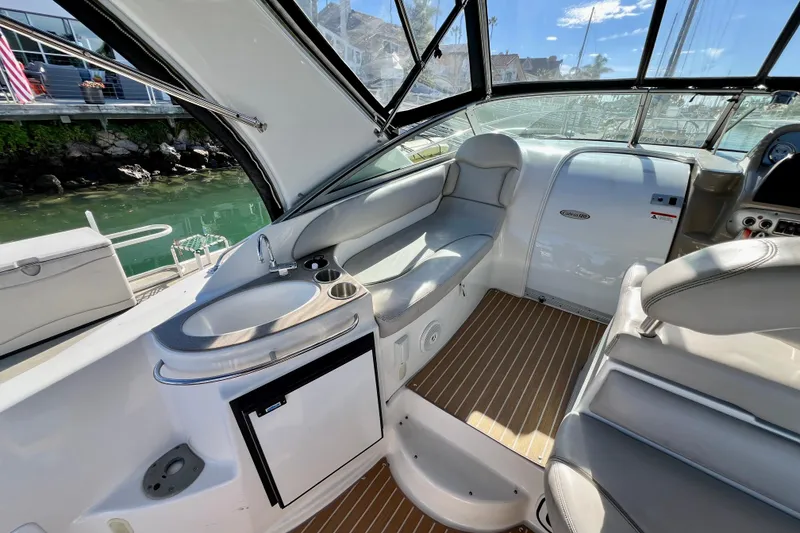 Slide: The Image of 2007 Larson Cabrio 310 boat interior with seating, sink, and helm, docked by the water. - 16