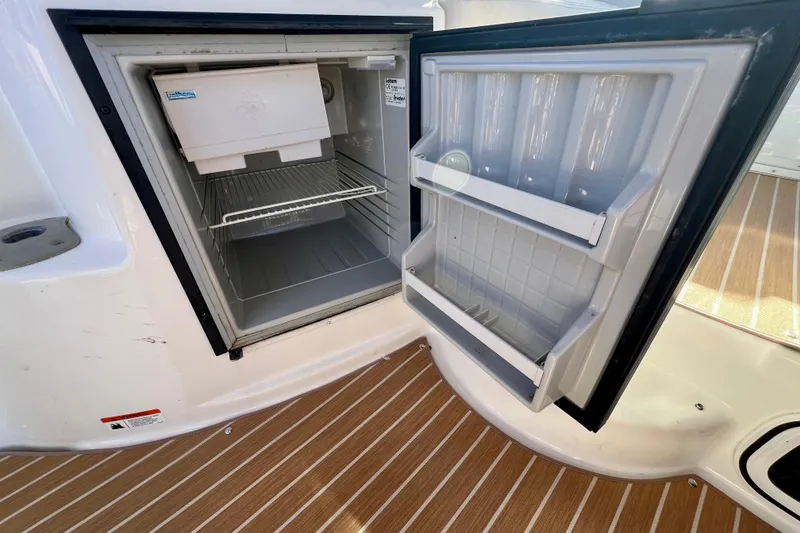 Slide: The Image of Open refrigerator on 2007 Larson Cabrio 310 boat, showcasing interior shelves and ice maker. - 18