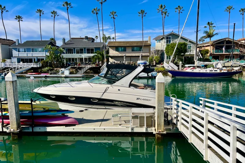 Slide: The Image of 2007 Larson Cabrio 310 docked in a scenic marina with palm trees and waterfront homes. - 2