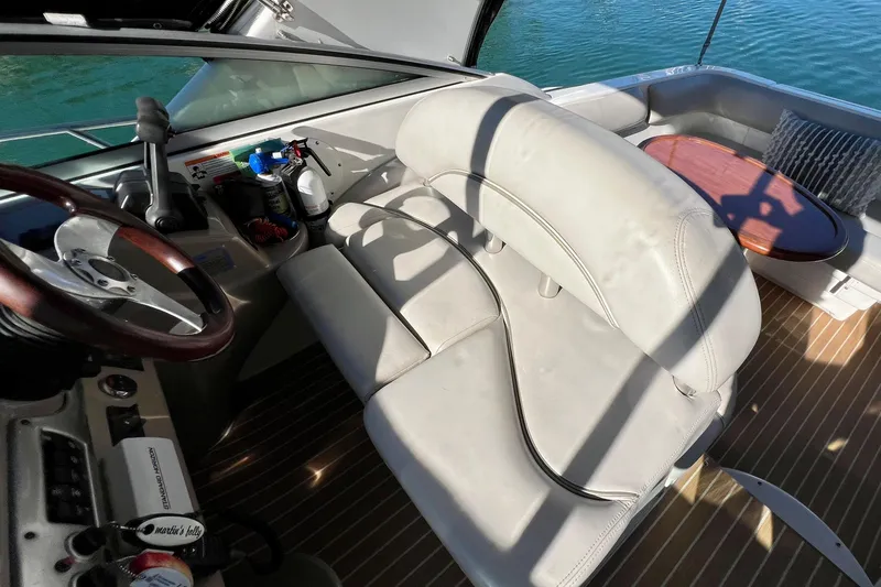 Slide: The Image of 2007 Larson Cabrio 310 boat interior with steering wheel, seating, and wooden table. - 22
