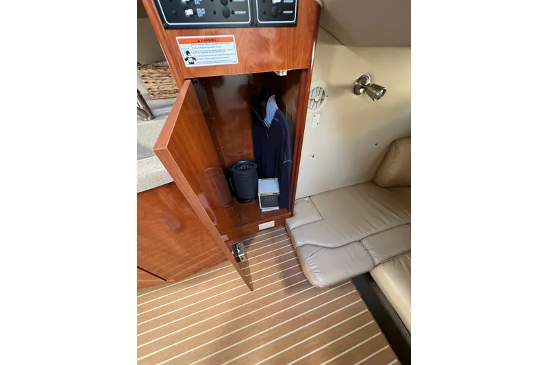 Slide: The Image of 2007 Larson Cabrio 310 interior with open wooden cabinet and beige seating. - 35