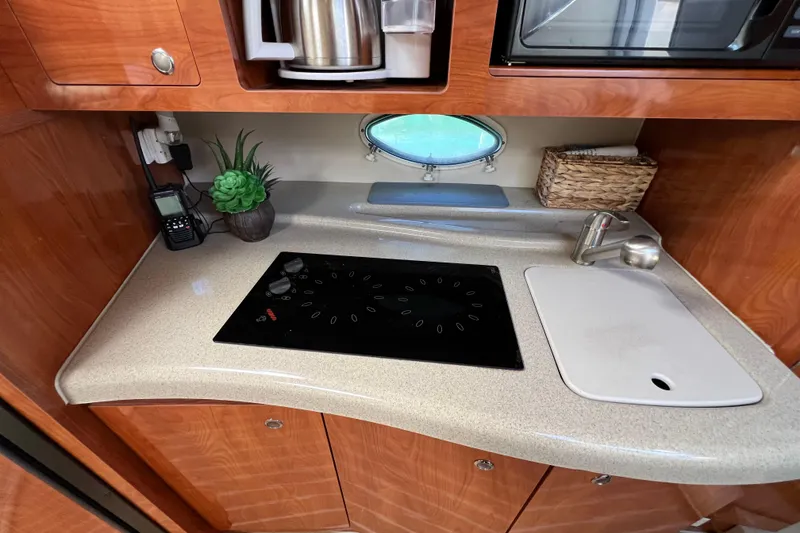 Slide: The Image of 2007 Larson Cabrio 310 boat kitchen with stove, sink, and wooden cabinetry. - 38