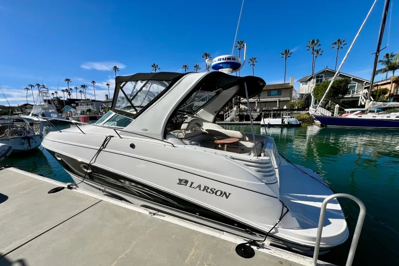 Slide: The Image of 2007 Larson Cabrio 310 boat docked in a marina under clear blue skies. - 4
