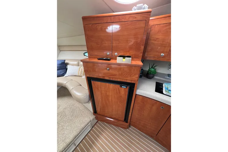 Slide: The Image of 2007 Larson Cabrio 310 cabin interior with wood cabinetry and compact fridge. - 40