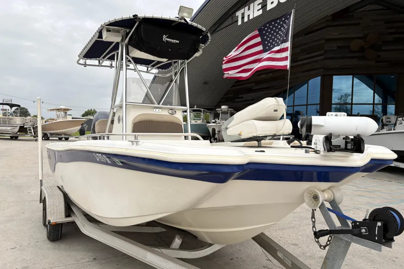 Slide: The Image of 2014 NauticStar 210 Coastal boat on trailer with American flag, parked outside dealership. - 10