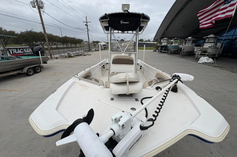 Slide: The Image of 2014 NauticStar 210 Coastal boat with trolling motor, docked near showroom and American flag. - 11