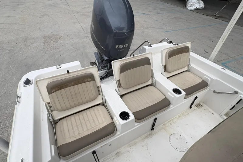 Slide: The Image of 2014 NauticStar 210 Coastal boat with three beige seats and Yamaha 150 outboard motor. - 21