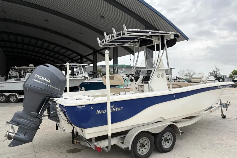 Slide: The Image of 2014 NauticStar 210 Coastal boat with Yamaha engine on trailer, parked near a marina. - 4