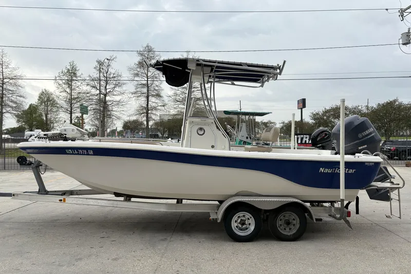 Slide: The Image of 2014 NauticStar 210 Coastal boat on trailer, featuring blue and white design with Yamaha engine. - 7