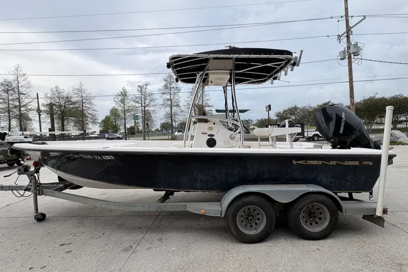 Slide: The Image of 2000 Kenner 21 VISION boat on trailer with Mercury engine, parked outdoors. - 7