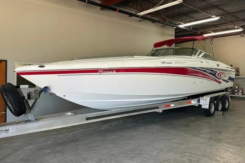 The Image of 2005 Baja 342 Boss speedboat on trailer in a garage, featuring red and white design. - 0
