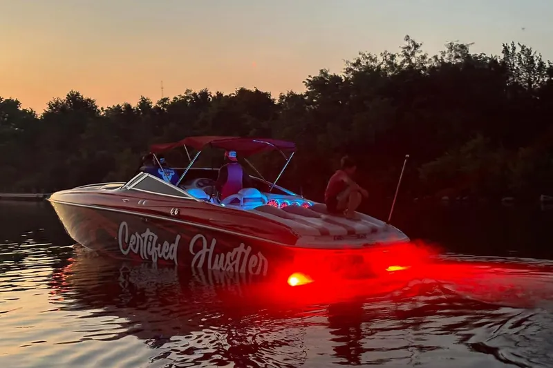 Slide: The Image of 2005 Baja 342 Boss boat with vibrant red lights at sunset on a calm lake. - 11