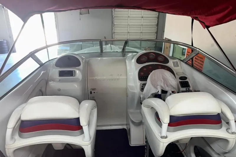 Slide: The Image of Interior of a 2005 Baja 342 Boss boat with white seating and dashboard controls. - 4
