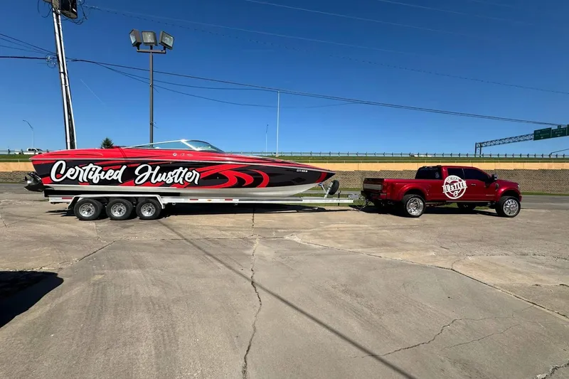 Slide: The Image of Red 2005 Baja 342 Boss boat on trailer, labeled "Certified Hustler," hitched to matching truck. - 9