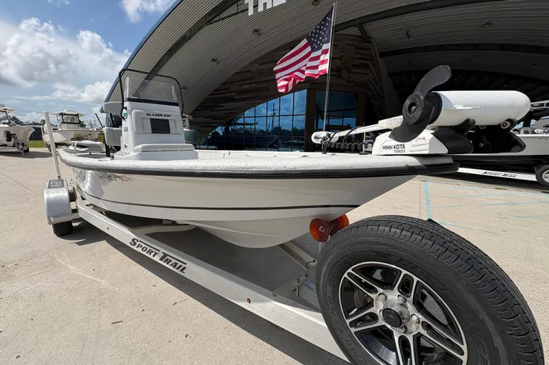 Slide: The Image of 2020 Blazer Bay 2170 boat on trailer with American flag, parked outdoors. - 10