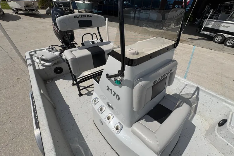 Slide: The Image of 2020 Blazer Bay 2170 boat interior with seating and console, parked outdoors. - 15