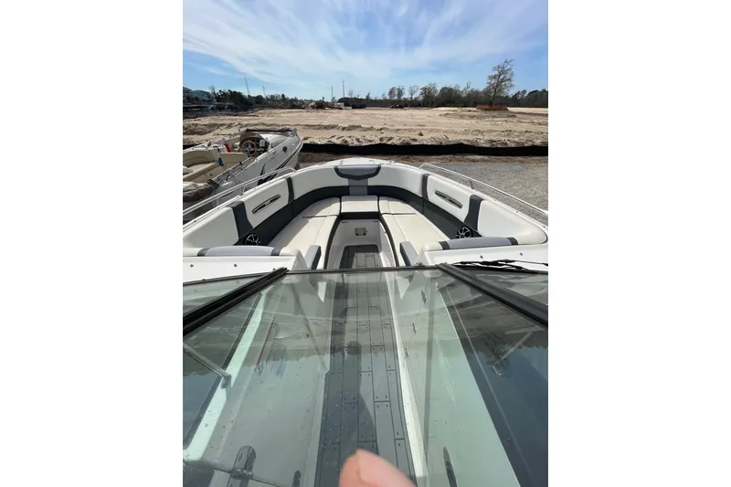 Slide: The Image of 2019 Chaparral 297 SSX boat interior with seating, parked on sandy terrain. - 2