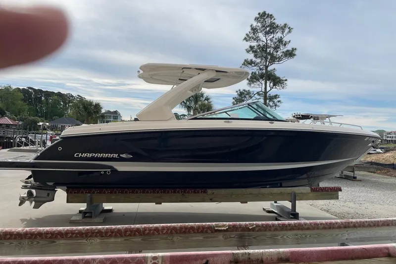 Slide: The Image of 2019 Chaparral 297 SSX boat on display at a marina with trees in the background. - 40