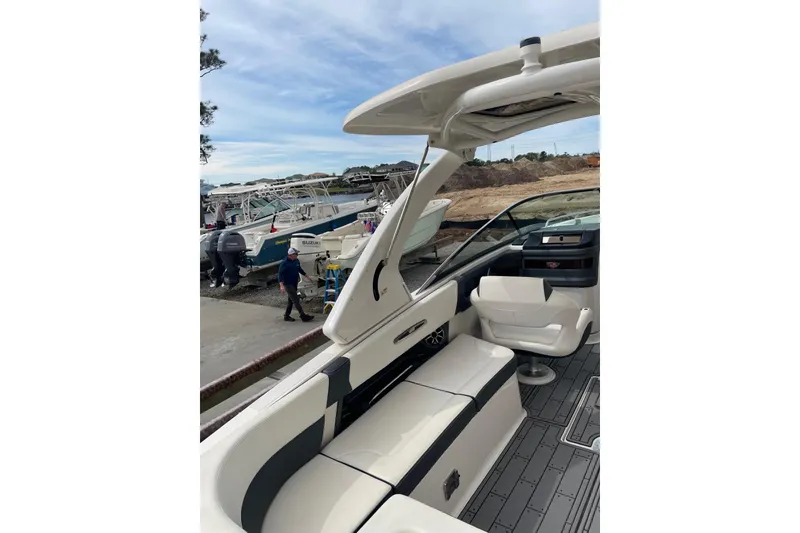 Slide: The Image of 2019 Chaparral 297 SSX boat interior with seating and helm, docked near other boats. - 9