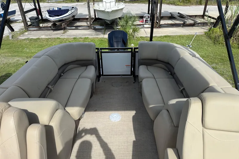 Slide: The Image of 2023 Regency 230 DL3 pontoon boat interior with beige seating and spacious layout. - 17