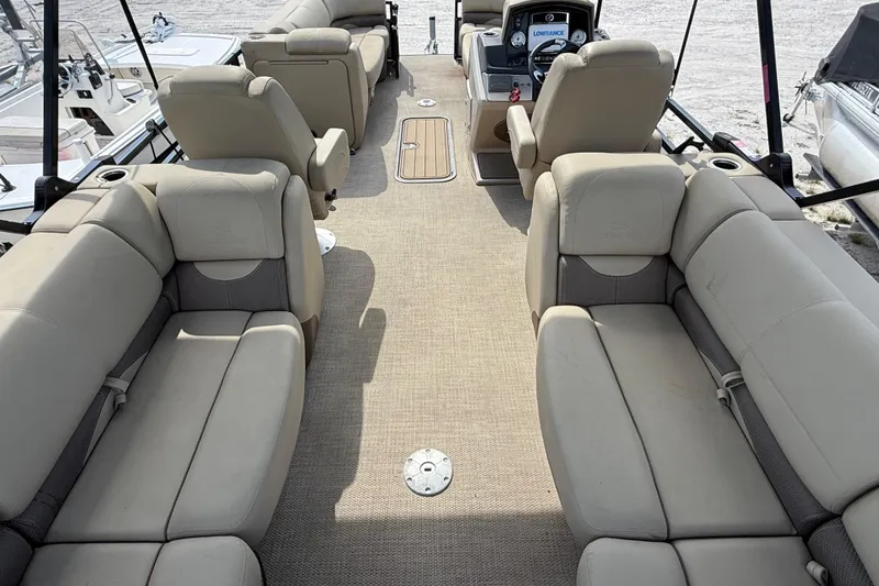 Slide: The Image of 2023 Regency 230 DL3 pontoon boat interior with beige seating and modern dashboard. - 26