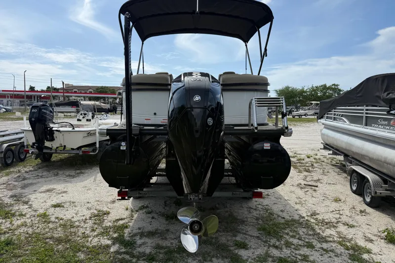 Slide: The Image of 2023 Regency 230 DL3 pontoon boat with outboard motor, parked on gravel lot. - 4