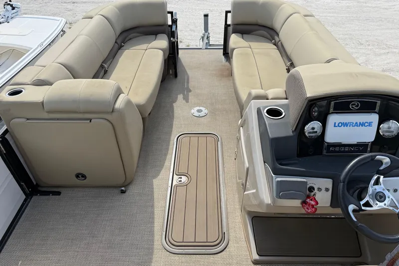 Slide: The Image of 2023 Regency 230 DL3 pontoon boat interior with beige seating and modern dashboard. - 45