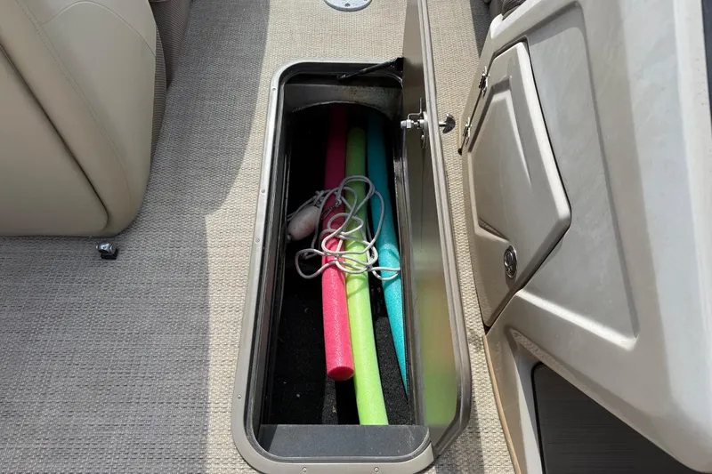 Slide: The Image of Open storage compartment on 2023 Regency 230 DL3 boat with pool noodles and rope. - 47