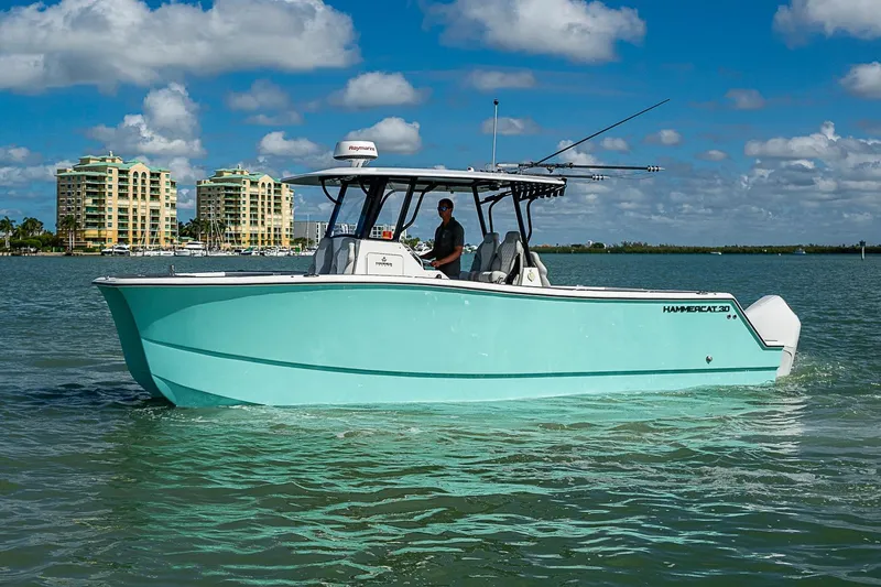 Slide: The Image of 2025 Hammer Yachts 30 boat cruising on a sunny day with buildings in the background. - 10