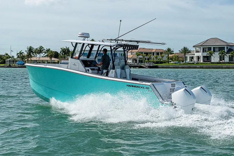 Slide: The Image of 2025 Hammer Yachts 30 cruising on water near luxury waterfront homes. - 15