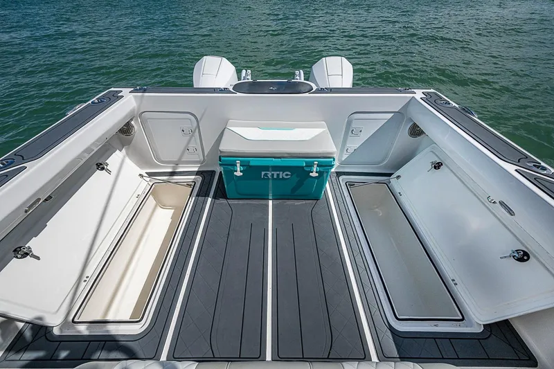 Slide: The Image of 2025 Hammer Yachts 30 boat deck with storage compartments and cooler, on calm water. - 21