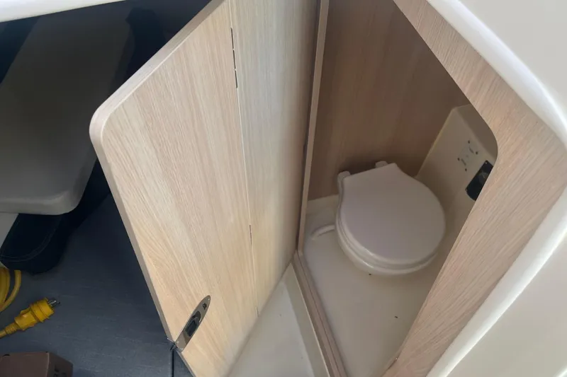 Slide: The Image of 2025 Bayliner Trophy T25 Pilothouse interior with compact marine toilet. - 11
