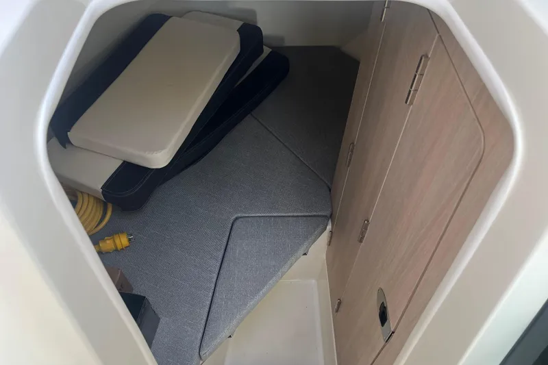 Slide: The Image of 2025 Bayliner Trophy T25 Pilothouse cabin interior with cushions and storage space. - 12