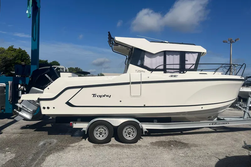 Slide: The Image of 2025 Bayliner Trophy T25 Pilothouse boat on trailer under clear blue sky. - 5