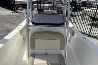 Slide: The Image of 2023 NauticStar 2302 Legacy boat interior with seating and console, docked outdoors. - 10