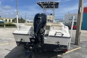 Slide: The Image of 2023 NauticStar 2302 Legacy boat with outboard motor, parked outdoors. - 6