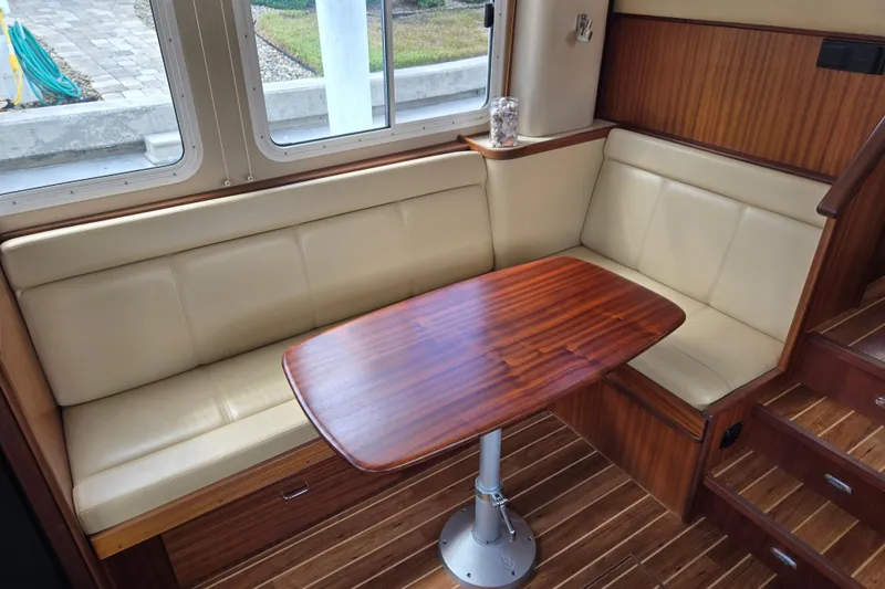 Slide: The Image of Interior of 2009 American Tug 34, featuring a cozy dining area with wood table. - 16