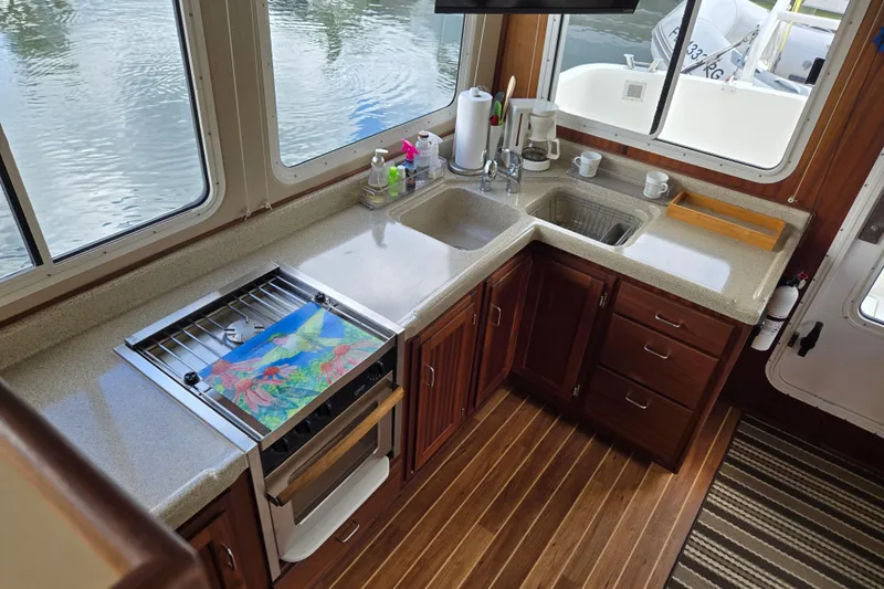Slide: The Image of 2009 American Tug 34 Rare Flybridge Model kitchen with wooden cabinets and large windows. - 18
