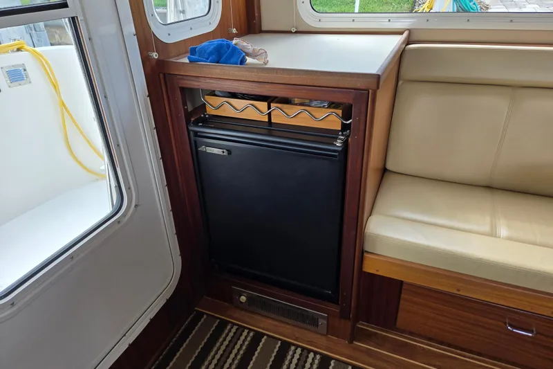 Slide: The Image of Interior of 2009 American Tug 34, featuring a compact fridge and seating area. - 27