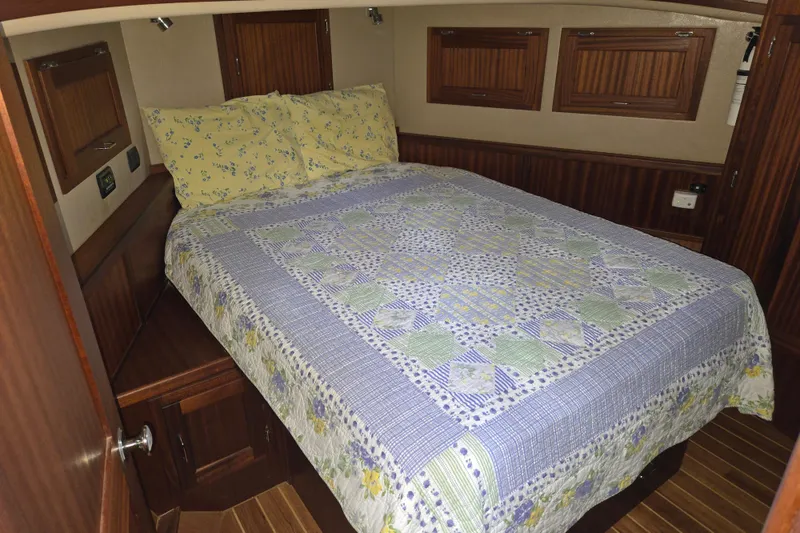 Slide: The Image of Cozy cabin interior of 2009 American Tug 34, featuring a patterned quilt and wooden accents. - 9