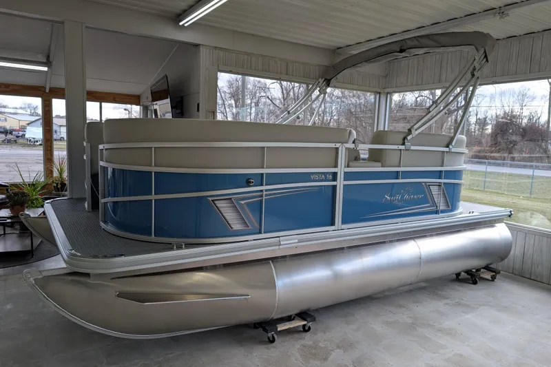 The Image of 2026 SunChaser Vista 16 LR pontoon boat in showroom, featuring sleek blue design. - 0